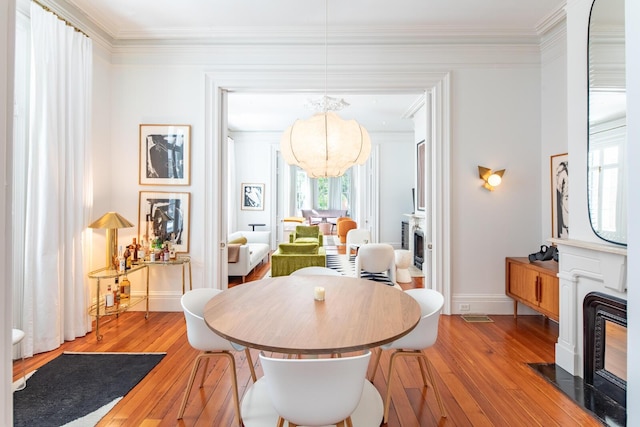 155 Wentworth St Unit A, Charleston, SC 29401 - dining area with an inviting chandelier, a fireplace with flush hearth, light wood finished floors, and crown molding