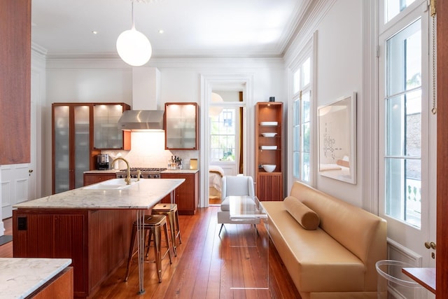 155 Wentworth St Unit A, Charleston, SC 29401 - kitchen with a sink, wood-type flooring, brown cabinetry, tasteful backsplash, and a kitchen bar