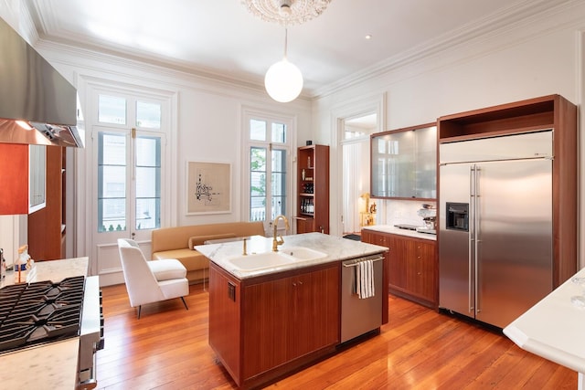 155 Wentworth St Unit A, Charleston, SC 29401 - kitchen featuring wall chimney range hood, brown cabinetry, a sink, ornamental molding, and stainless steel appliances