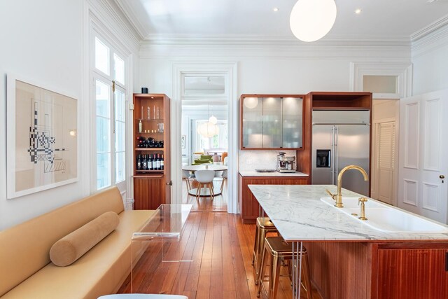 155 Wentworth St Unit A, Charleston, SC 29401 - kitchen featuring wood-type flooring, glass insert cabinets, a breakfast bar area, built in fridge, and a sink