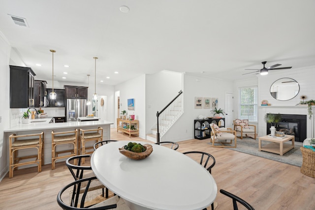 dining room featuring ceiling fan, sink, and light hardwood / wood-style flooring