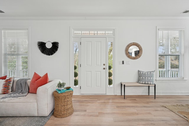 foyer entrance featuring light hardwood / wood-style flooring, ornamental molding, and a healthy amount of sunlight