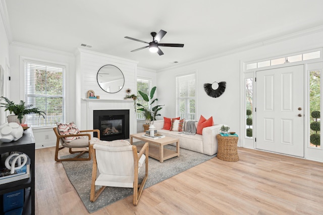 living room featuring plenty of natural light, ornamental molding, and light wood-type flooring