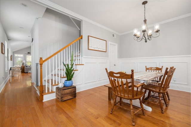 dining area featuring lofted ceiling, a chandelier, crown molding, and light hardwood / wood-style flooring