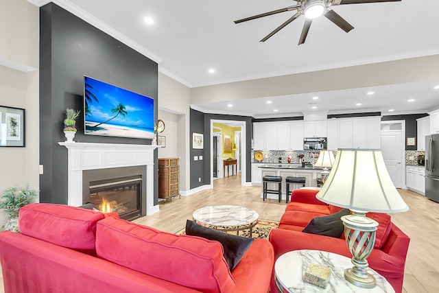 3115 Cross Vine Ln, Summerville, SC 29483 - living room with light wood-type flooring, a glass covered fireplace, recessed lighting, crown molding, and baseboards