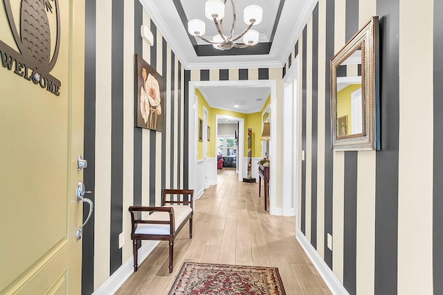 hall featuring a notable chandelier, light wood-style flooring, wallpapered walls, and crown molding