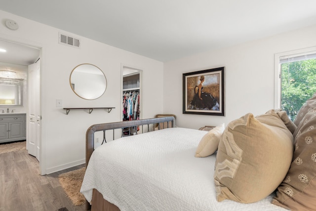 bedroom with a closet, ensuite bathroom, and hardwood / wood-style flooring