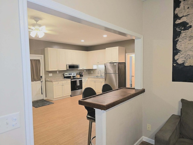 9489 Sidneys Rd, Round O, SC 29474 - kitchen with stainless steel appliances, a sink, ceiling fan, light wood-type flooring, and a breakfast bar area