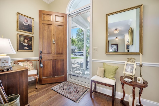 foyer entrance with baseboards, crown molding, and wood finished floors