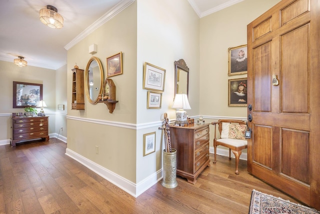foyer with wood finished floors, baseboards, and ornamental molding