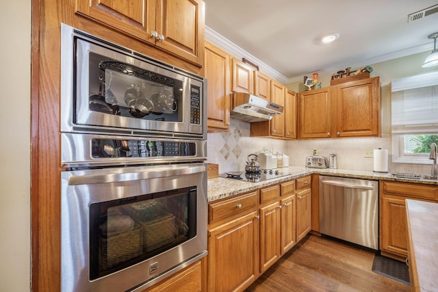 kitchen with visible vents, a sink, appliances with stainless steel finishes, under cabinet range hood, and light stone counters
