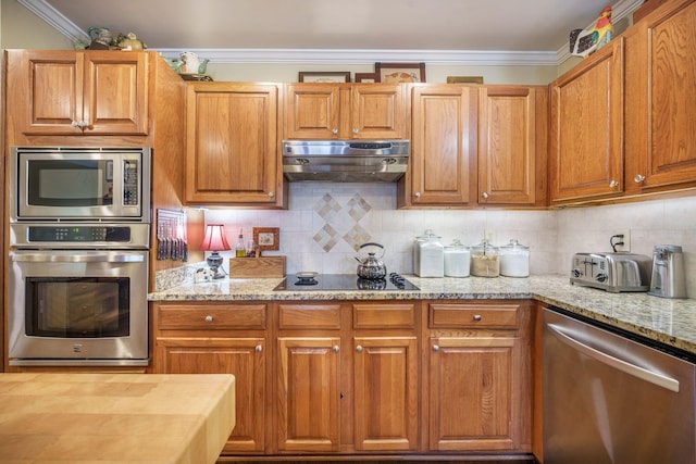 kitchen with tasteful backsplash, appliances with stainless steel finishes, under cabinet range hood, crown molding, and light stone counters