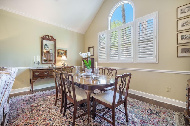 dining room with crown molding, baseboards, high vaulted ceiling, and wood finished floors
