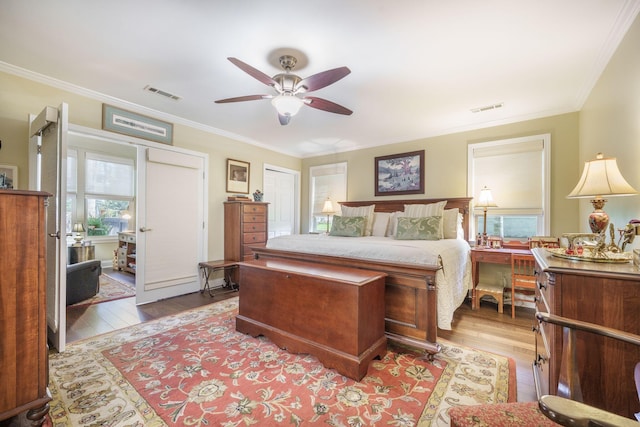 bedroom with ornamental molding, visible vents, a ceiling fan, and hardwood / wood-style flooring