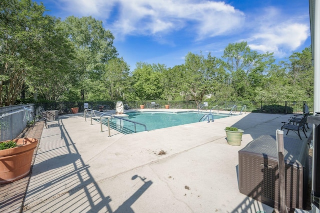 community pool with a patio area and fence