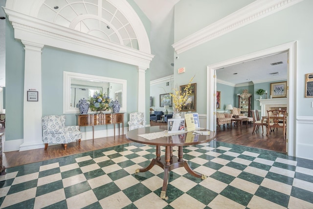 foyer entrance featuring ornamental molding, ornate columns, and wood finished floors
