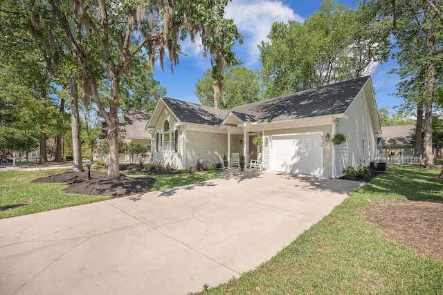 ranch-style home with roof with shingles, driveway, an attached garage, a front yard, and central AC
