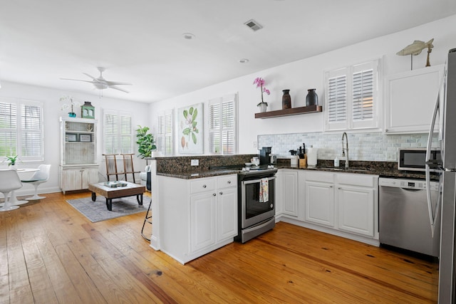 kitchen featuring a peninsula, white cabinets, stainless steel appliances, and a sink