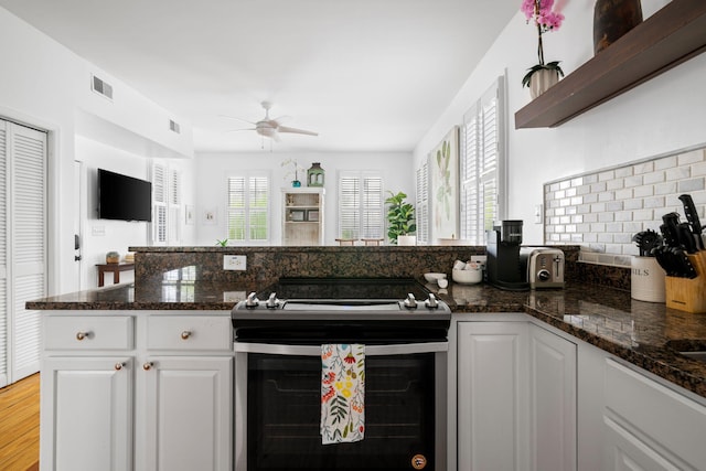 kitchen with white cabinets, dark stone countertops, and stainless steel electric stove