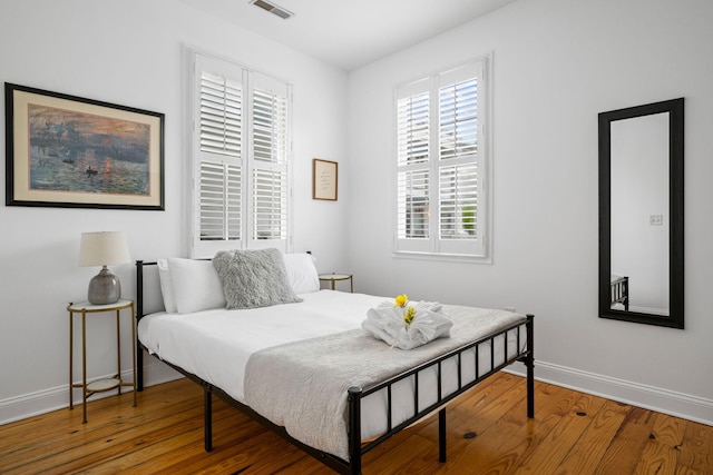 bedroom featuring wood finished floors, visible vents, and baseboards