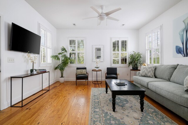 living room with baseboards, visible vents, a ceiling fan, and wood finished floors