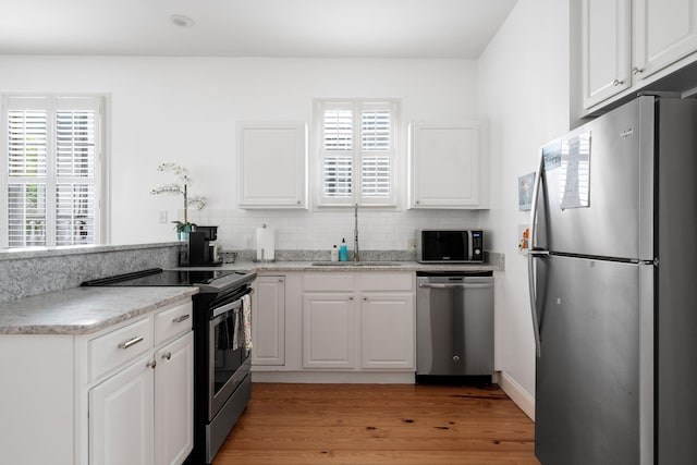 kitchen with stainless steel appliances, a wealth of natural light, a sink, and white cabinetry