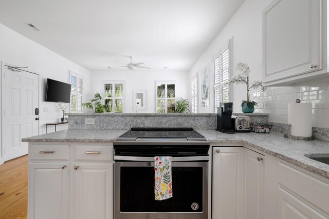 kitchen with visible vents, electric stove, white cabinetry, and decorative backsplash