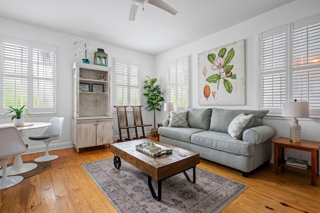 living area featuring light wood finished floors, plenty of natural light, a ceiling fan, and baseboards