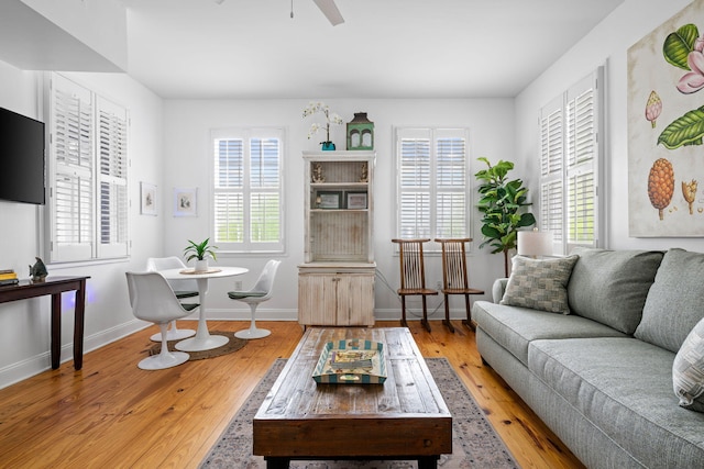 living area with ceiling fan, baseboards, and hardwood / wood-style flooring