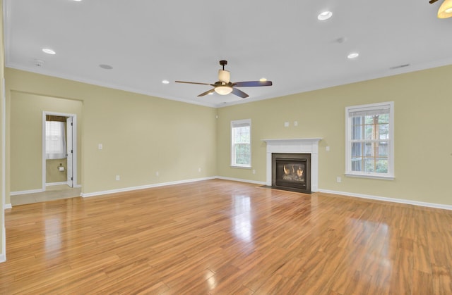 unfurnished living room featuring ceiling fan, ornamental molding, and light wood-type flooring