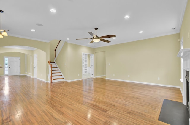 unfurnished living room with light hardwood / wood-style floors, ornamental molding, and ceiling fan