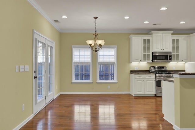 kitchen with white cabinetry, appliances with stainless steel finishes, dark hardwood / wood-style floors, ornamental molding, and pendant lighting