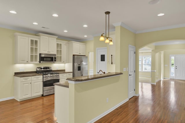 kitchen with kitchen peninsula, hanging light fixtures, ornamental molding, and stainless steel appliances