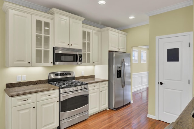 kitchen featuring dark hardwood / wood-style floors, dark stone counters, stainless steel appliances, and ornamental molding