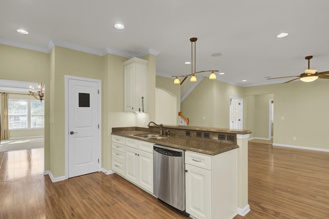 kitchen with stainless steel dishwasher, kitchen peninsula, sink, and white cabinetry