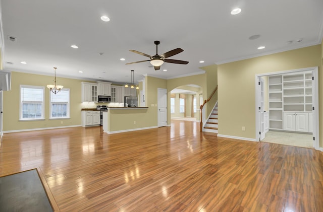 unfurnished living room with light wood-type flooring, ceiling fan with notable chandelier, and ornamental molding