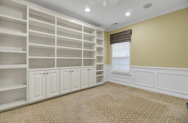 carpeted empty room with built in shelves and ornamental molding