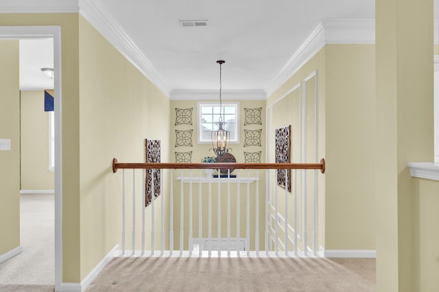 hall with an inviting chandelier, crown molding, and light colored carpet