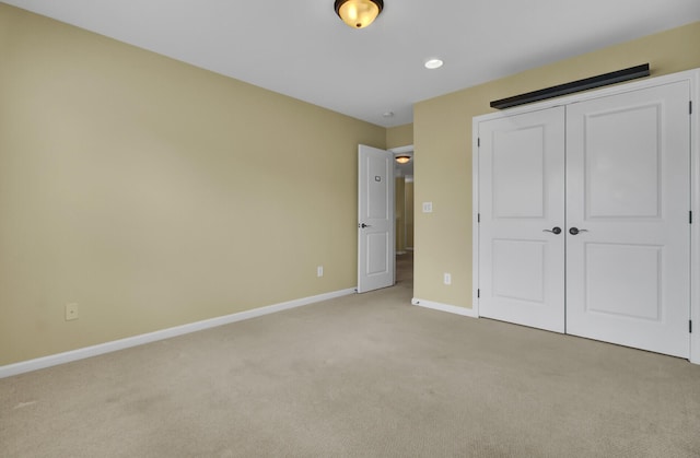 unfurnished bedroom with light carpet and a closet