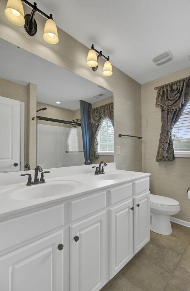 bathroom with vanity, toilet, and a shower with door