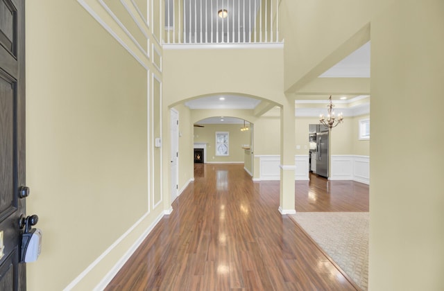 entryway featuring dark hardwood / wood-style flooring, ornamental molding, a towering ceiling, and a notable chandelier