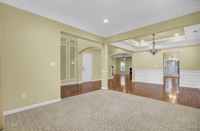 spare room featuring carpet floors, ceiling fan with notable chandelier, crown molding, and a raised ceiling