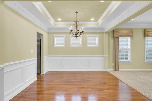 empty room with an inviting chandelier, a tray ceiling, and ornamental molding