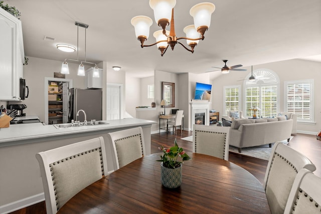 dining space featuring sink, ceiling fan with notable chandelier, and dark hardwood / wood-style flooring