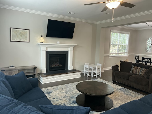 living room with a glass covered fireplace, ornamental molding, wood finished floors, and visible vents