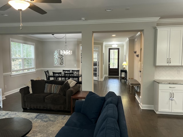 living room with dark wood-style floors, a ceiling fan, baseboards, and crown molding