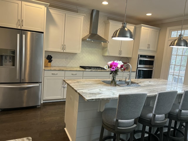 kitchen featuring stainless steel appliances, a sink, backsplash, wall chimney exhaust hood, and crown molding