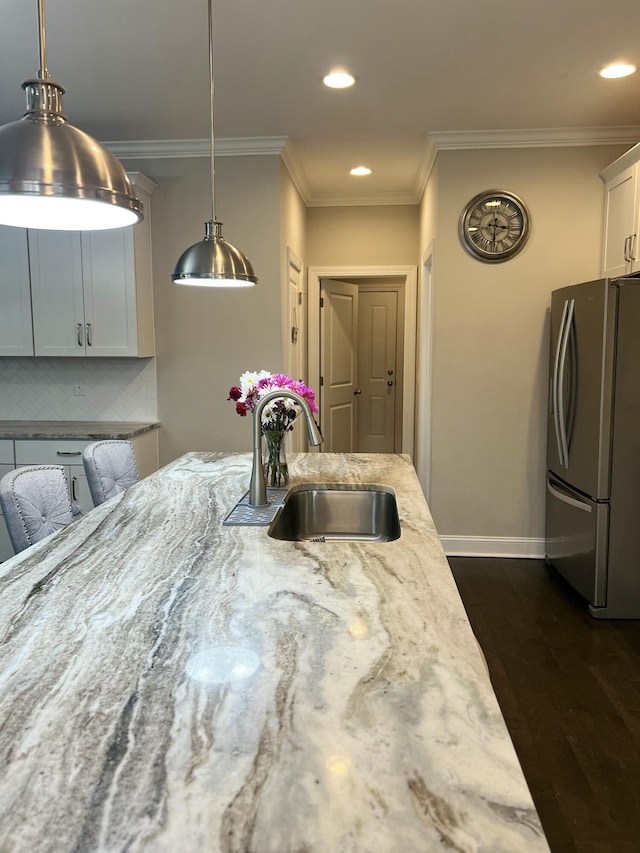 kitchen with dark wood-style flooring, a sink, stainless steel fridge with ice dispenser, ornamental molding, and decorative backsplash