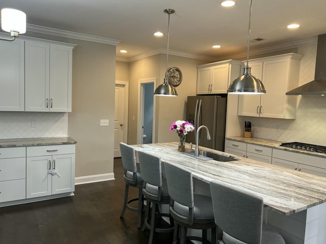 kitchen with light stone counters, dark wood-style flooring, stainless steel appliances, wall chimney range hood, and a sink