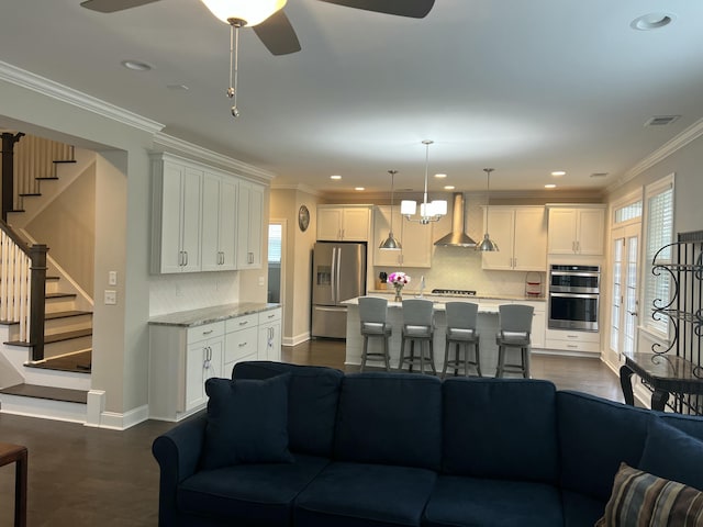 living room with a ceiling fan, baseboards, visible vents, stairway, and crown molding